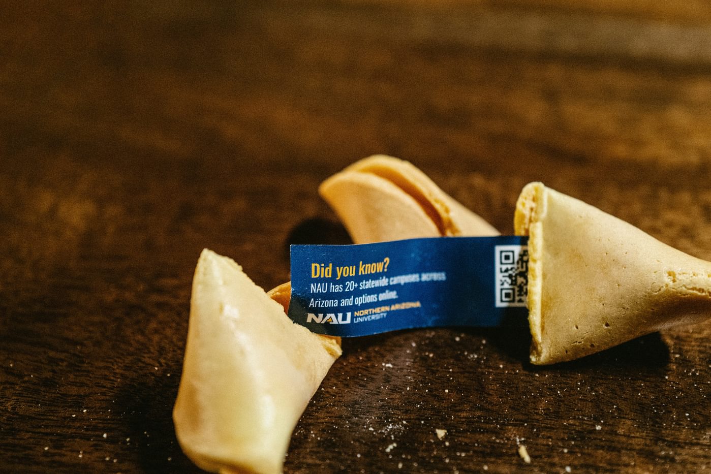 Close-up on broken fortune cookie with NAU fortune. Fortune says "Did you know? NAU has 20+ statewide campuses across Arizona and options online."